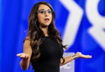Defamation Suit Raises Questions Over $100K Claim Woman speaking on stage with arms outstretched