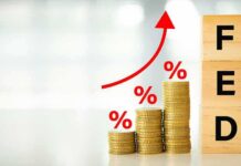 Massive Shake-Up: Viral Gold Forecast Sparks Questions Stacks of coins with rising red arrow and wooden blocks spelling FED