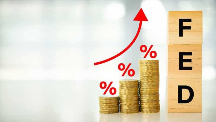 shutterstock_2280564225 Stacks of coins with rising red arrow and wooden blocks spelling FED