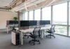 Modern open-plan office with workstations by large windows