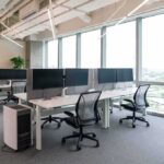 Modern open-plan office with workstations by large windows