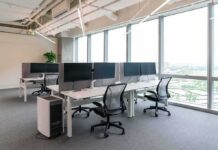 Modern open-plan office with workstations by large windows