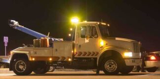 Tow truck with flashing lights parked at night