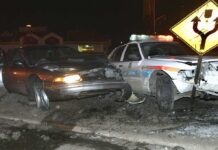 A damaged car and a police vehicle involved in a nighttime accident