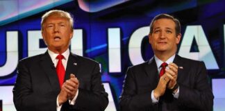 two men in suits clapping on a brightly lit stage