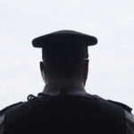 Teen Killed After 50-Minute Bridge Standoff security officer seen from behind wearing cap and earpiece