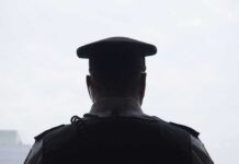 security officer seen from behind wearing cap and earpiece