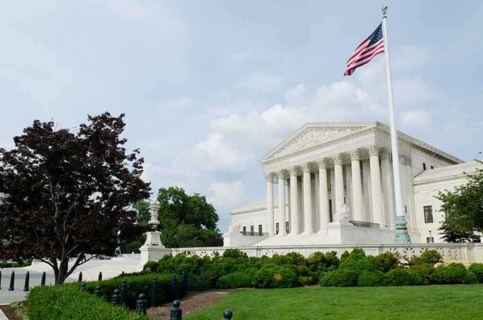 The U.S. Supreme Court building with an American flag and landscaped grounds